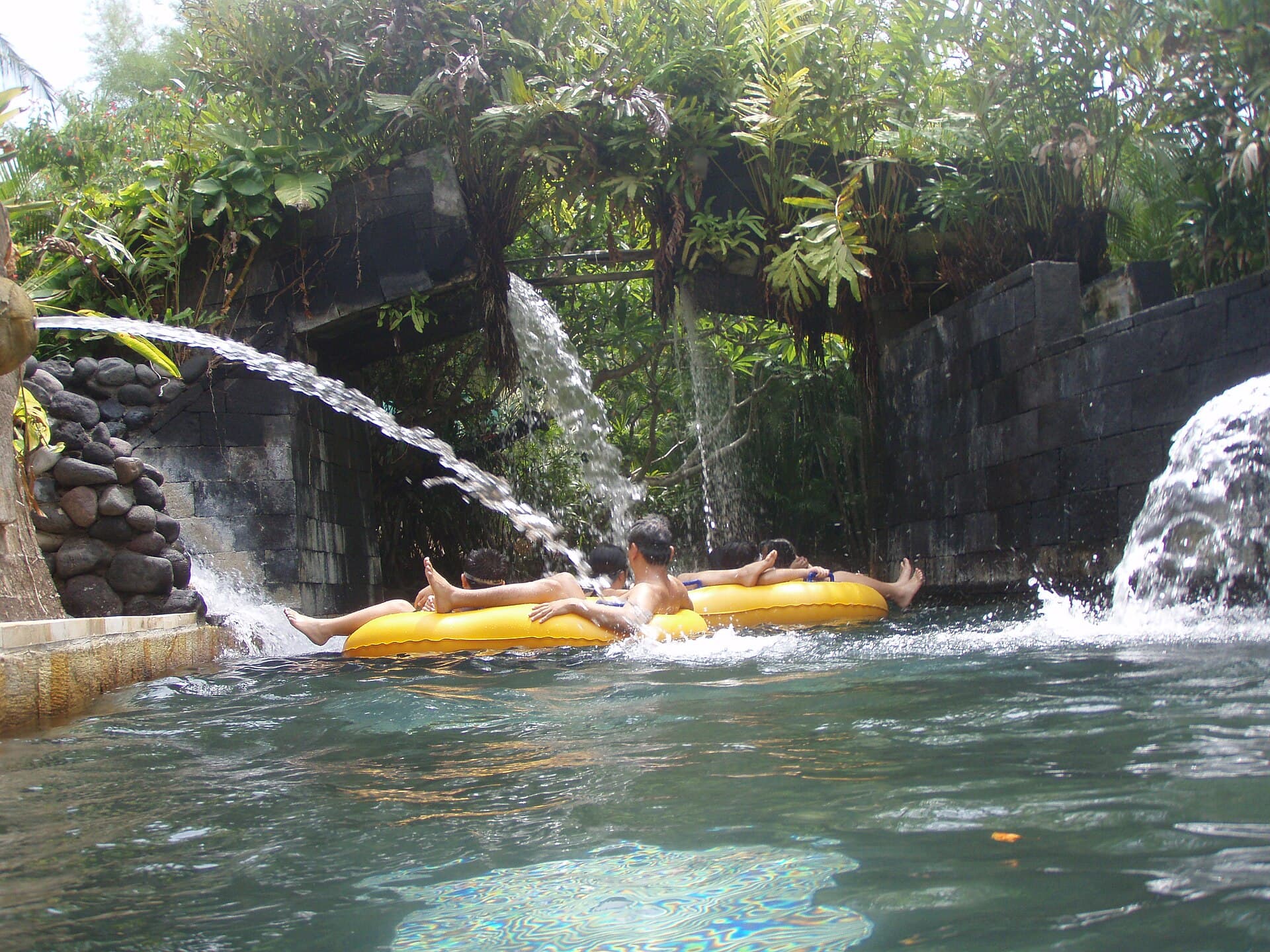 Gasten glijden op een gele band door een glijbaan in Waterbom Bali